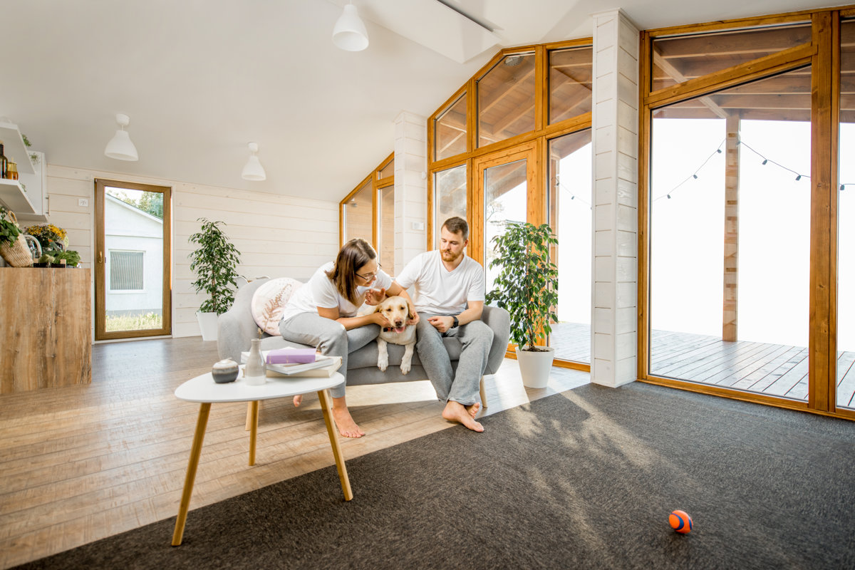 Wide view on the cozy living room interior of the house with young couple and their dog indoors
