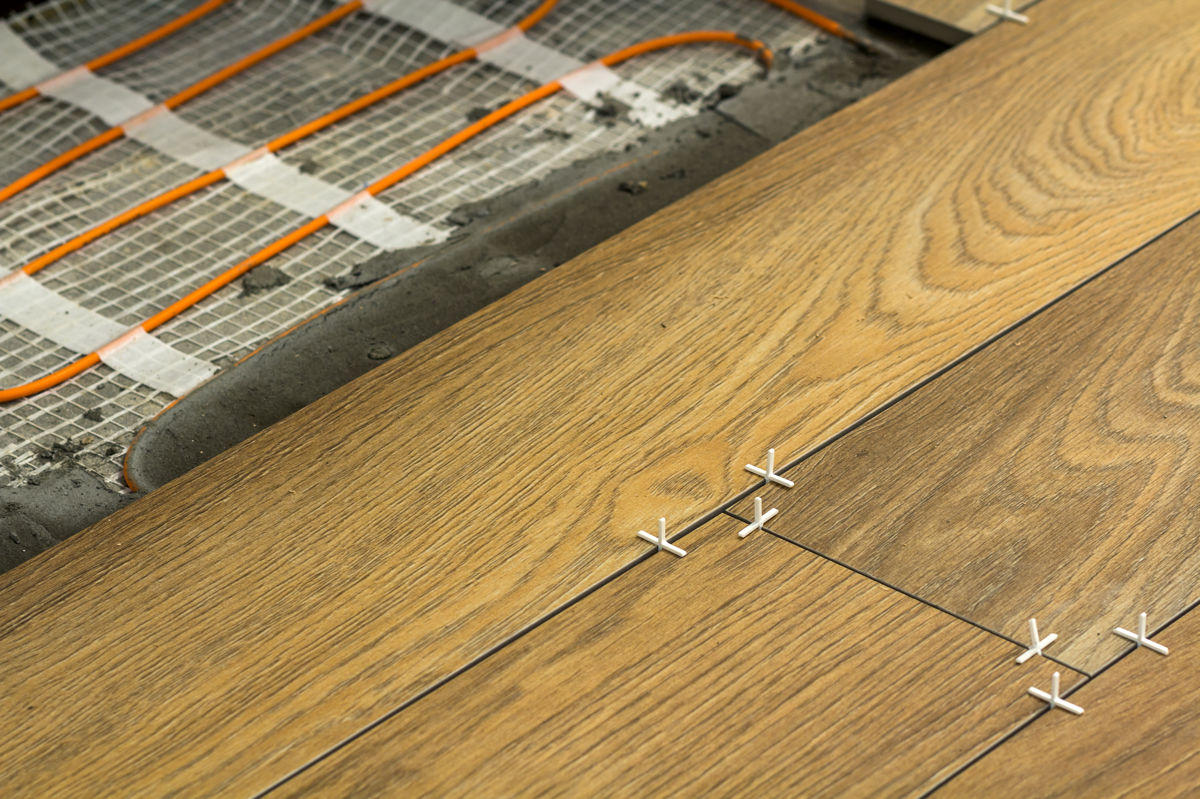 Installation of ceramic tiles and heating elements in warm tile floor. Renovation and improvement concept.